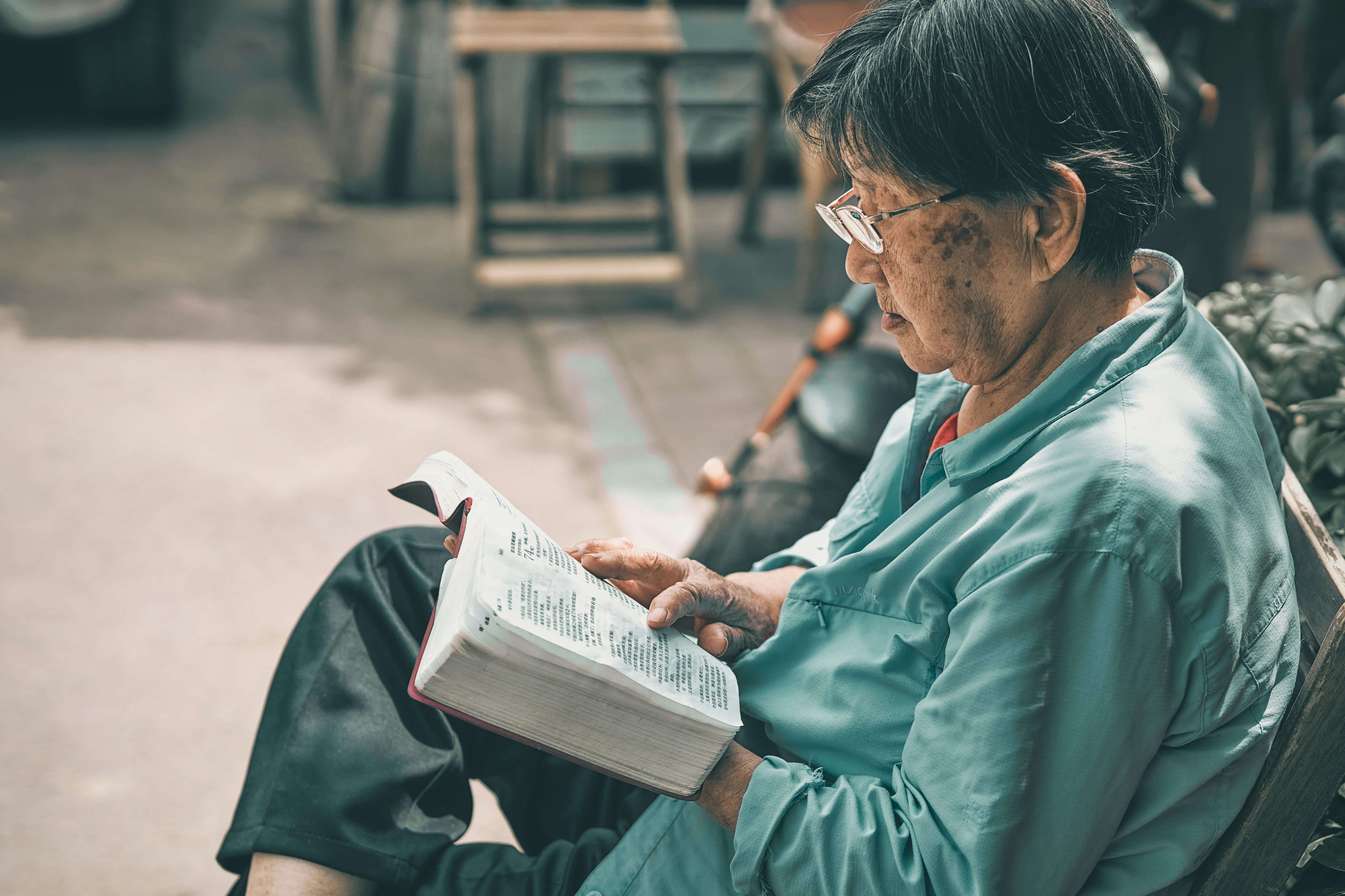 man in teal dress shirt reading book